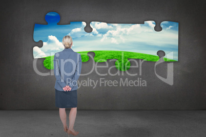 Composite image of businesswoman standing with hands behind back