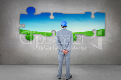 Composite image of businessman with helmet turning his back to c
