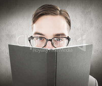 Composite image of geeky man looking over book