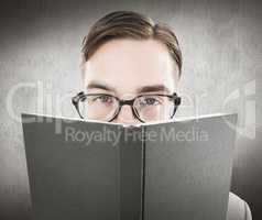 Composite image of geeky man looking over book