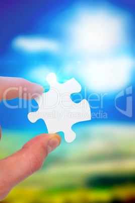 Composite image of hand holding jigsaw piece