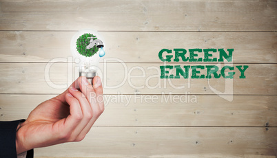 Composite image of hand holding environmental light bulb Composite image of hand holding environmental light bulb