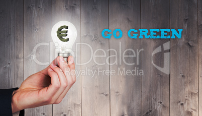 Composite image of hand holding environmental light bulb