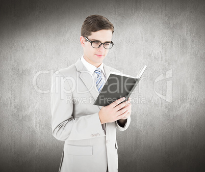 Composite image of geeky businessman reading black book