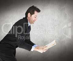 Composite image of businessman lying on the floor while reading