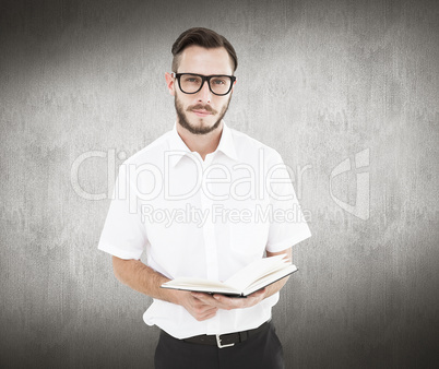 Composite image of geeky young man reading from black book