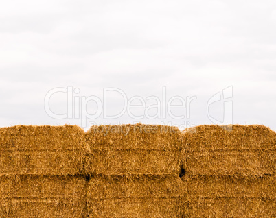 Six stacked yellow hay bales on overcast sky