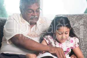 Granddaughter and grandfather reading book