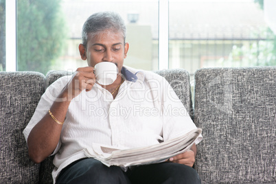 Indian drinking coffee and reading newspaper