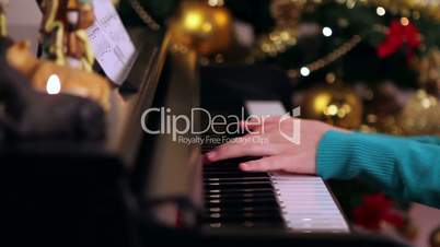Girl with green playing piano near Christmas tree
