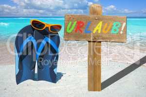 Flip Flops, Sonnenbrille und Holzschild mit Text URLAUB