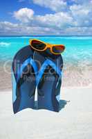 Sonnenbrille auf blauen Flip Flops am Strand