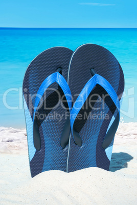 Blaue Flip Flops stecken im Sand am Traumstrand