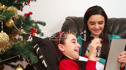 Young girls using a digital tablet near Christmas tree