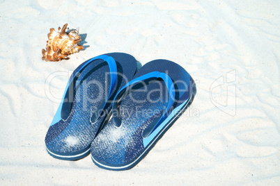 Flip Flops und Muschel liegen am Sandstrand