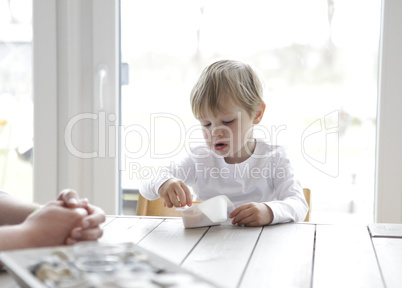 Junge ißt Jogurt am Tisch