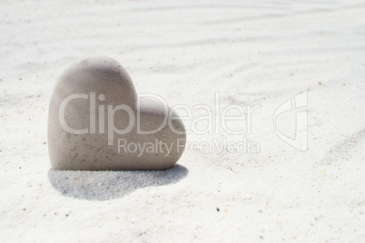 Großes Herz aus Stein steckt im Sandstrand