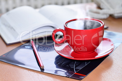 Red cup of coffee on the desk in the office