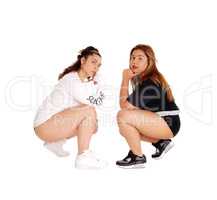 Two pretty young woman crouching.