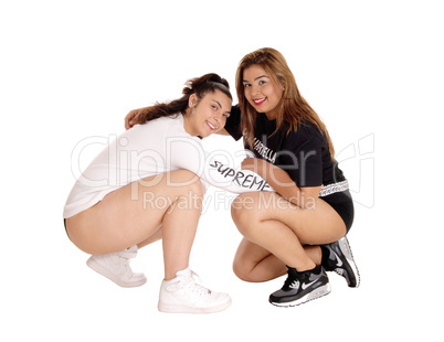 Two lovely young woman crouching.