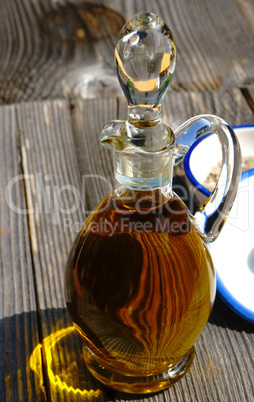 Glaskaraffe mit Olivenöl vor rustikalem Hintergrund
