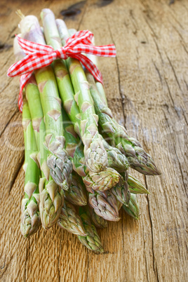 Bund grüner Spargel mit Schleife auf Holztisch