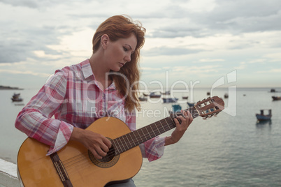 beautiful red-haired girl with a guitar