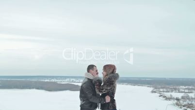 Young couple kissing by the river in winter weather