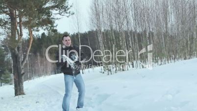 Couple having snowball fight in snow in winter forest, slowmotion