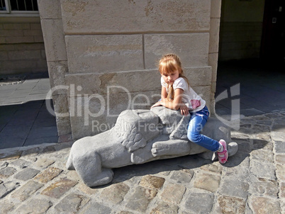 Small girl sitting on the lions sculpture