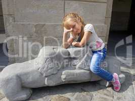 Little girl sitting on the lions sculpture