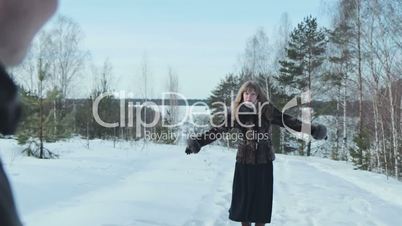 Couple having snowball fight in snow in winter forest, slowmotion