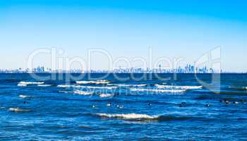 Waves breaking on lake with Toronto skyline on distant horizon