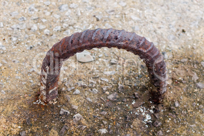 Rusted curved metal loop in concrete