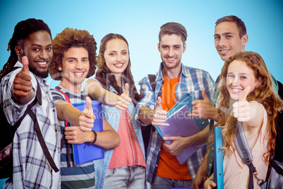 Composite image of smiling group of students doing thumbs up