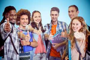 Composite image of smiling group of students doing thumbs up