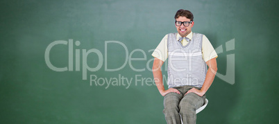 Composite image of geeky hipster sitting on stool