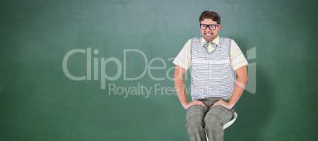 Composite image of geeky hipster sitting on stool