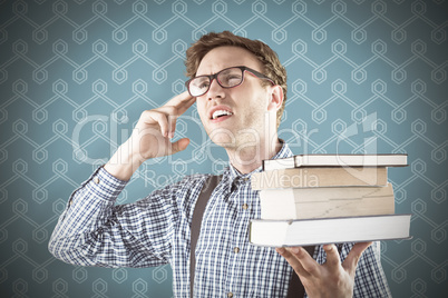 Composite image of geeky student holding a pile of books