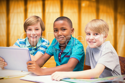 Composite image of cute pupils using tablet computer in library