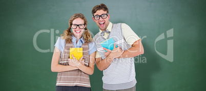 Composite image of geeky hipster couple holding books and smilin