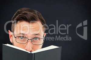 Composite image of young geek looking over black book