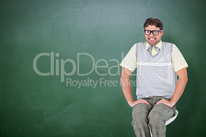 Composite image of geeky hipster sitting on stool