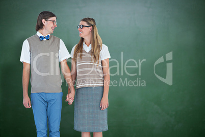 Composite image of geeky hipster couple holding hands and lookin