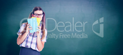 Composite image of geeky hipster hiding her face behind notepad