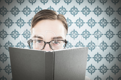 Composite image of geeky man looking over book