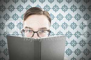 Composite image of geeky man looking over book