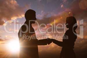Composite image of silhouette of business people shaking hands