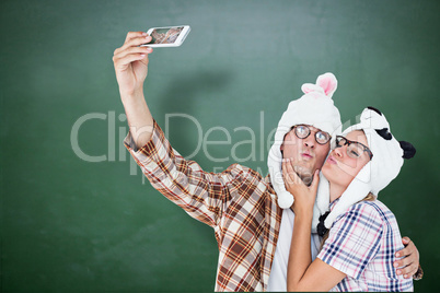 Composite image of geeky hipster couple taking selfie with smart