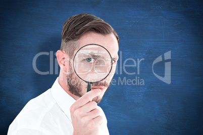 Composite image of geeky businessman looking through magnifying glass